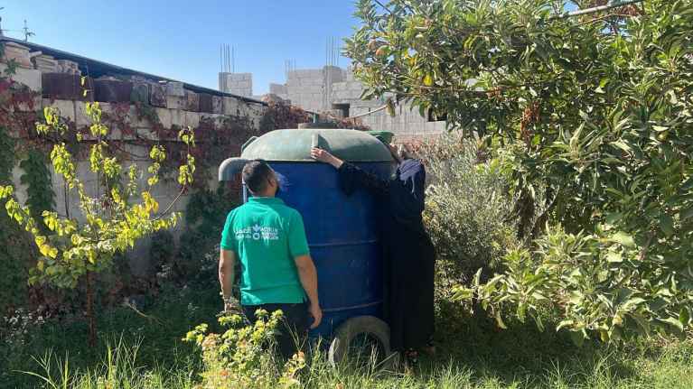 Sahar in her home garden shows how the biogas unit works.