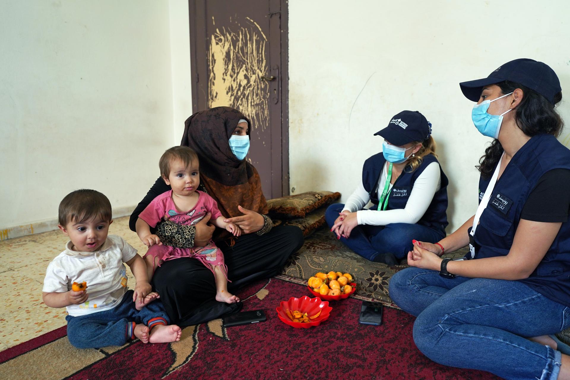 Una madre refugiada siria en el Líbano habla con trabajadoras humanitarias de Acción contra el Hambre junto a dos de sus bebés.