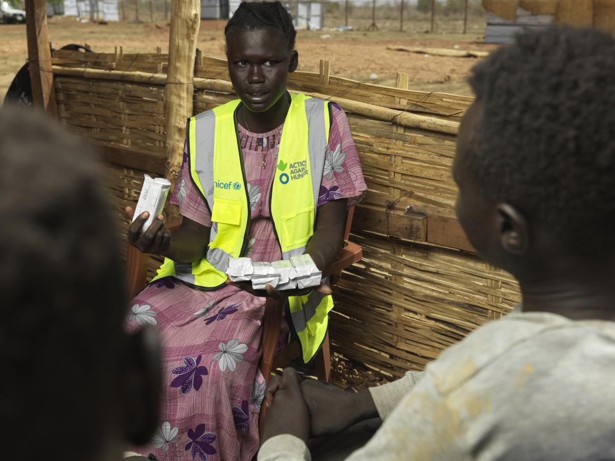 Mary Anok Juac da galletas energéticas a los recién llegados al puesto fronterizo de Majok Yinthiou, en Sudán del Sur. © Peter Caton para Acción contra el Hambre