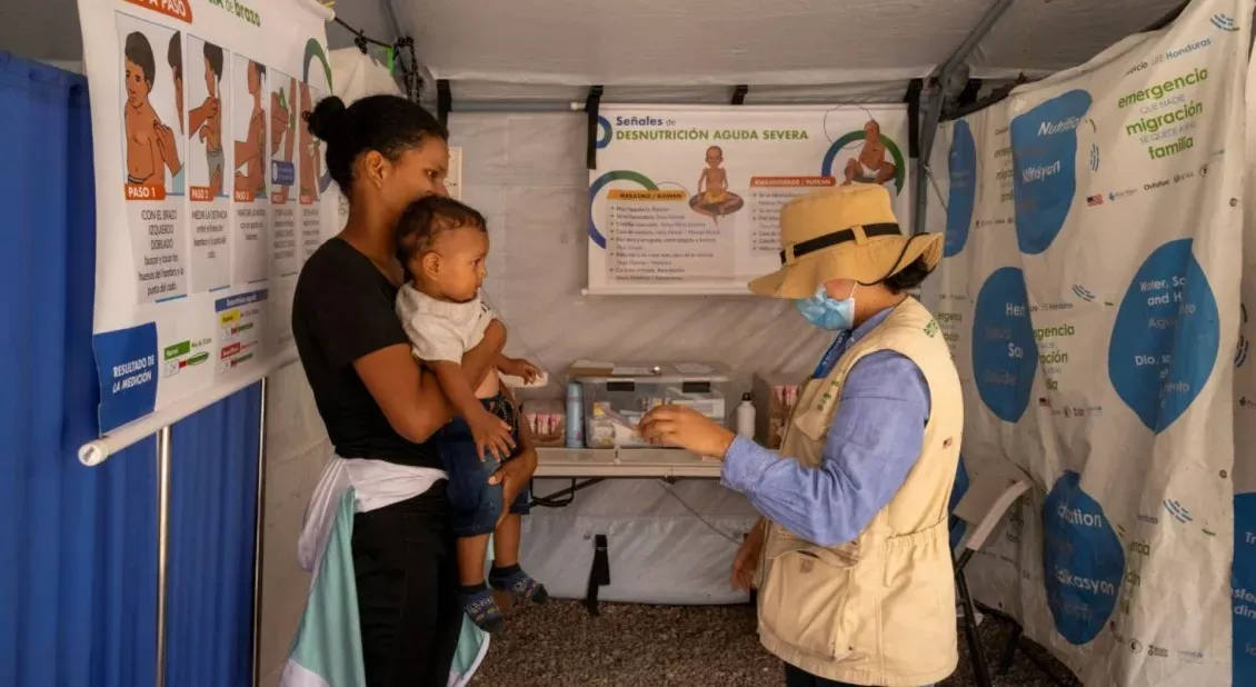 Mujer con su bebé recibiendo atención médica en un punto de descanso de la ruta migratoria en Centroamérica - Acción contra el Hambre