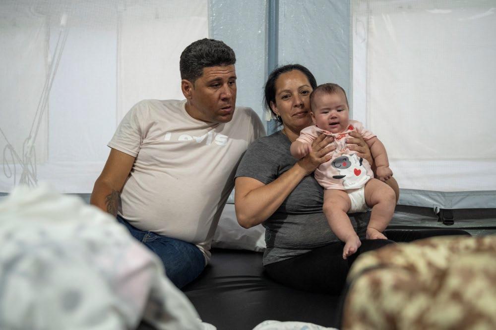 Hombre, mujer y bebé en un centro de descanso para migrantes en Centroamérica - Acción contra el Hambre