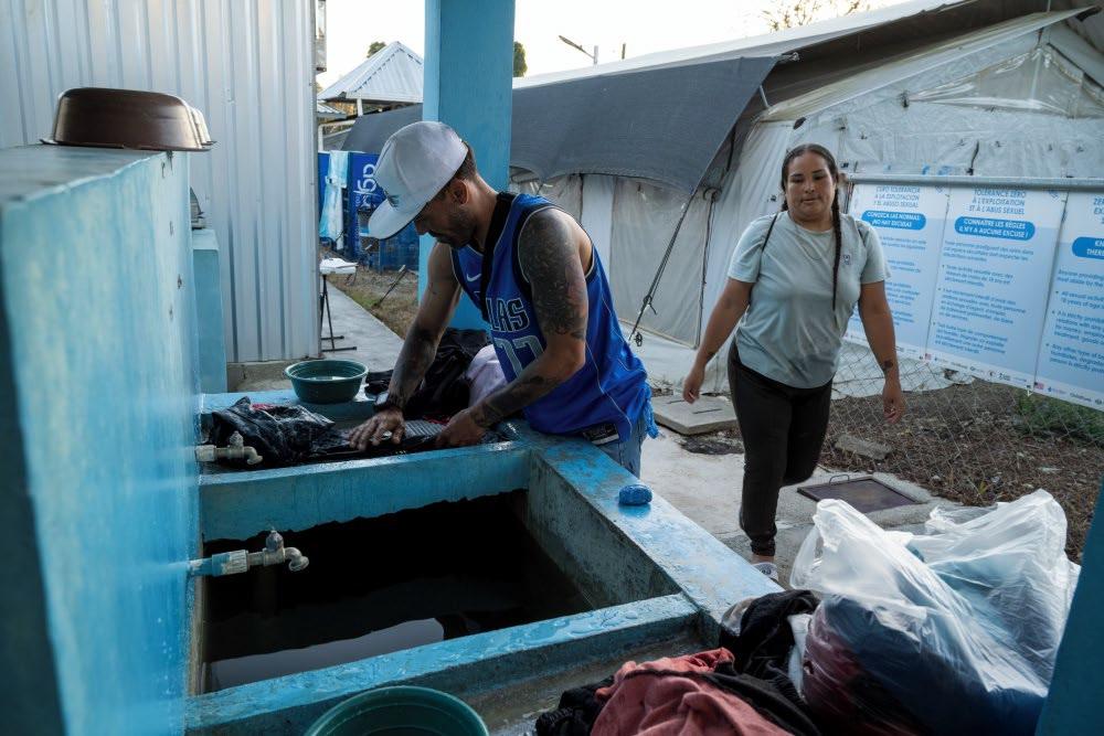 Hombre y mujer en un lavadero en un centro de descanso de migrantes - Honduras