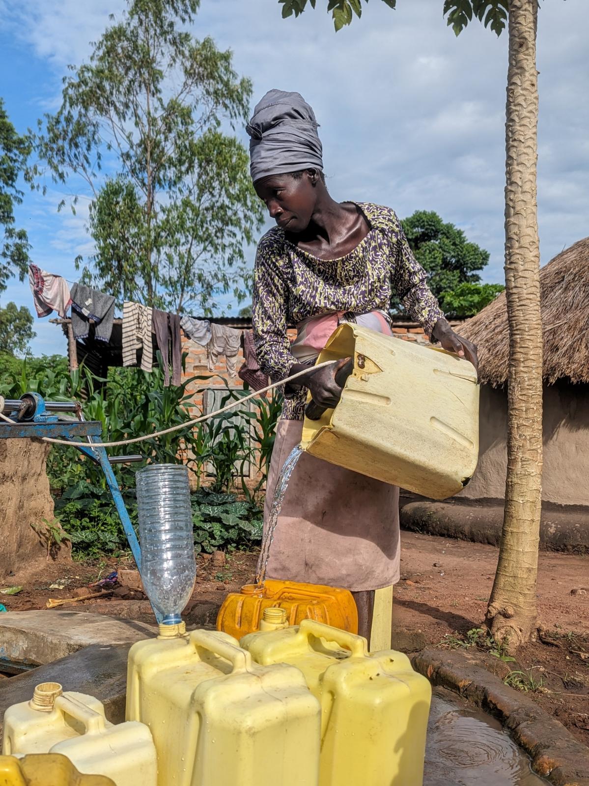 una mujer rellena garrafas de agua en una aldea de Uganda