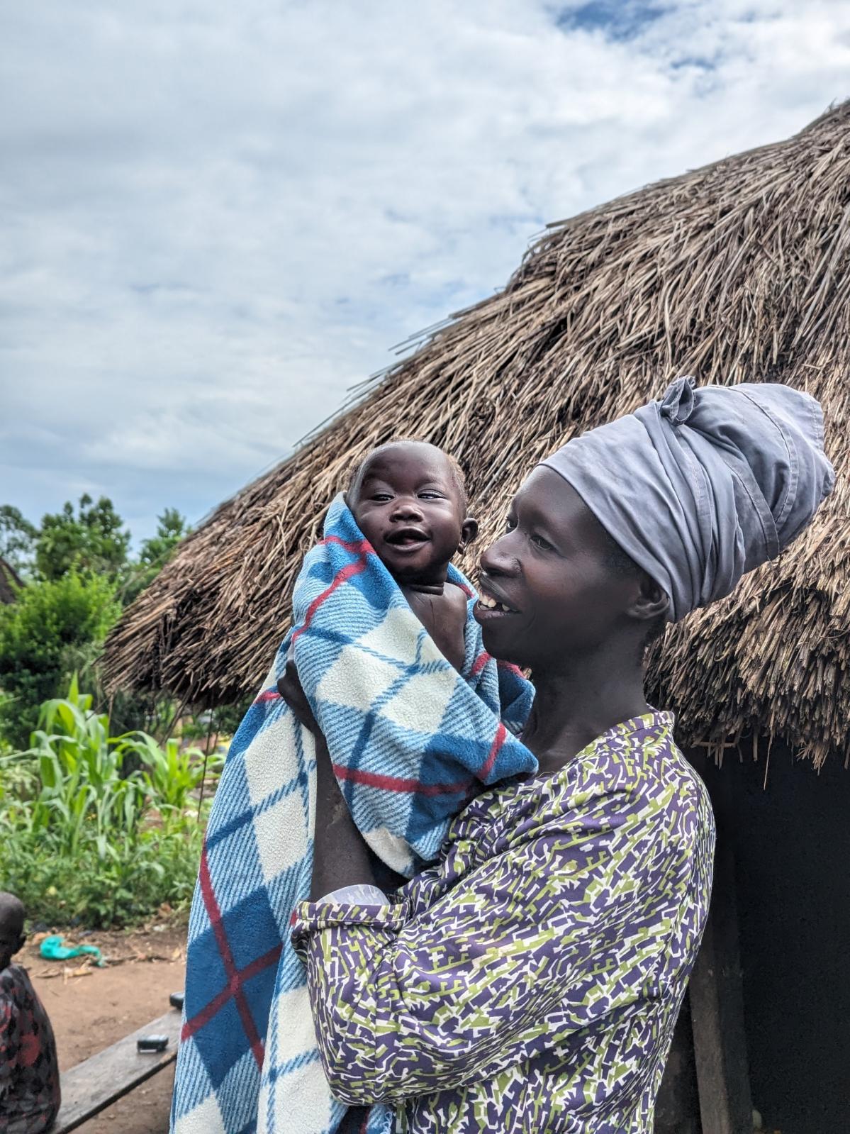 una madre coge a su hija en brazos en una aldea de Uganda