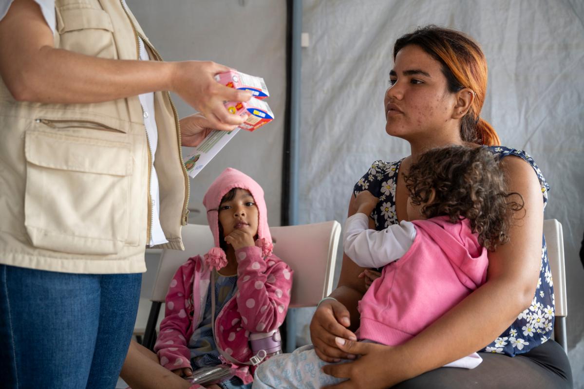 una madre joven migrante con sus niñas recibe tratamiento nutricional de una trabajadora de Acción contra el Hambre en Honduras