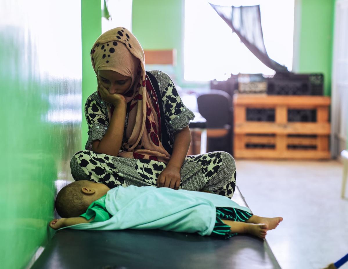 Una madre yemení mira a su hijo que va a ser examinado por el equipo de Acción contra el Hambre por un presunto caso de desnutrición