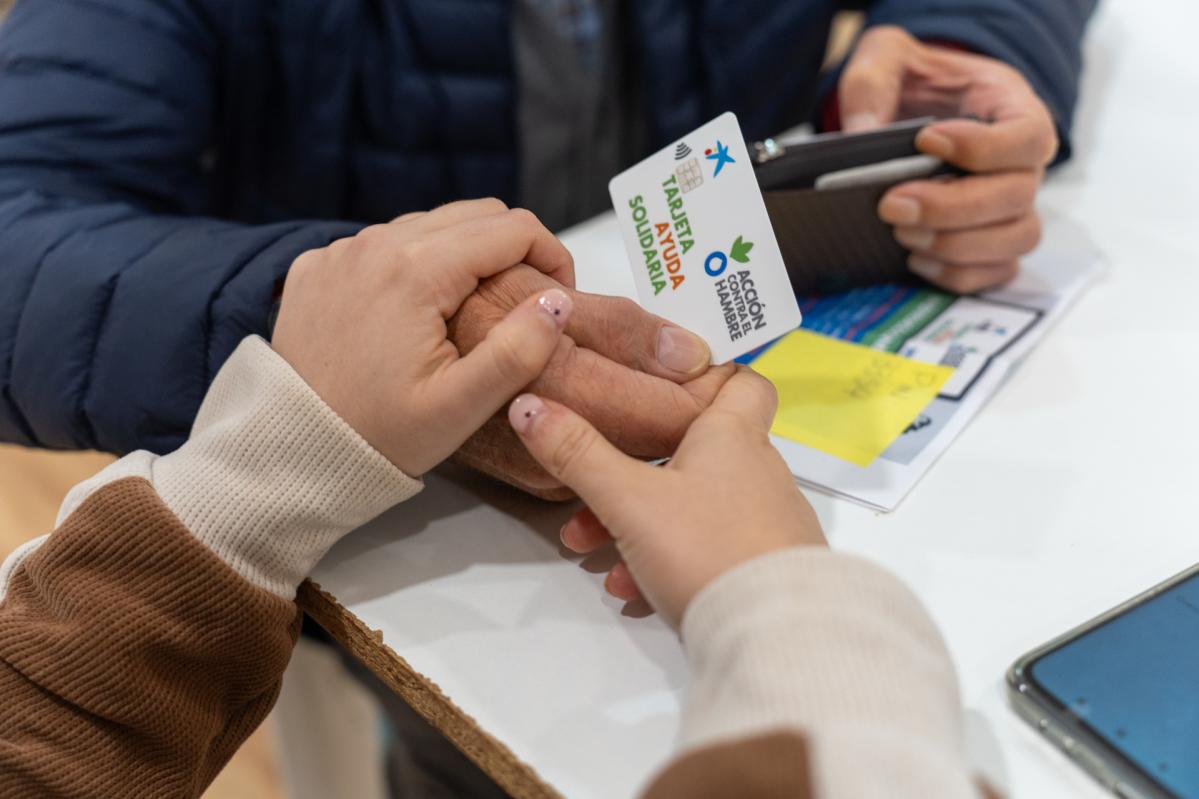 El equipo de Acción contra el Hambre proporciona una tarjeta solidaria a una persona afectada por la DANA