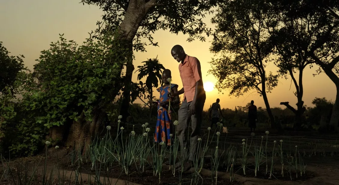 Chan enseña a su hija mayor, Adut Agany, sobre el arte de cultivar cebollas para que algún día ella pueda cultivarlas por sí misma.