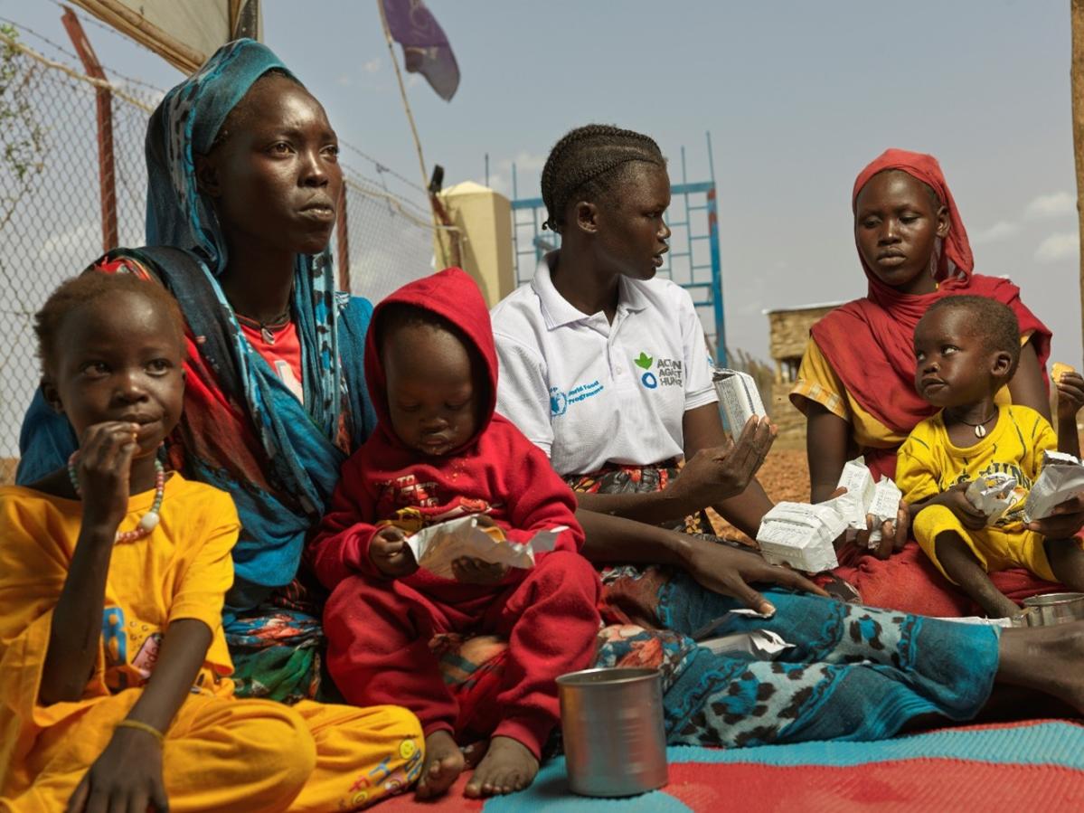 Adheet Akeen Alhia de 20 años, embarazada, y su hijo reciben galletas energéticas tras llegar al puesto fronterizo de Majok Yinthiou, en Sudán del Sur. 