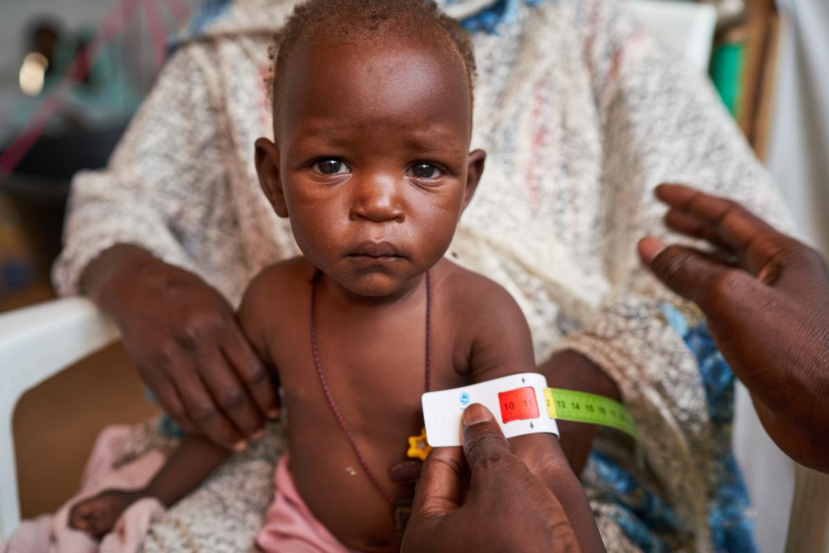 Niño mirando a cámara mientras le miden el brazo