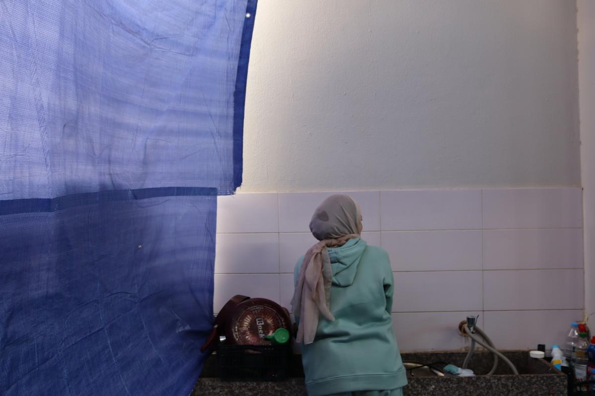 Hayat doing the dishes in the common kitchen at the collective shelter