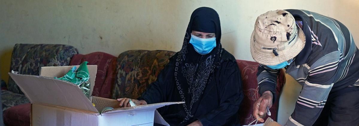 An adult Lebanese couple opens a box with humanitarian aid in Lebanon